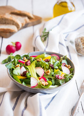 Fresh vegetable salad with radish, arugola, croutons on white wood