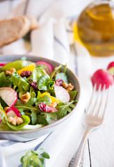 Fresh vegetable salad with radish, arugola, croutons on white wood