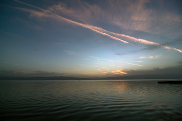 After sunset over Lake Ohrid with colorful clouds and traces of airplane.