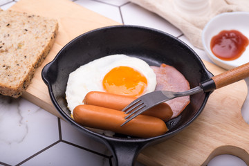 breakfast in pan with fried eggs, sausages, bacon, toasts and coffee