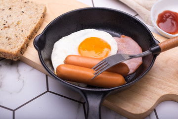 breakfast in pan with fried eggs, sausages, bacon, toasts and coffee