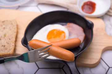 breakfast in pan with fried eggs, sausages, bacon, toasts and coffee