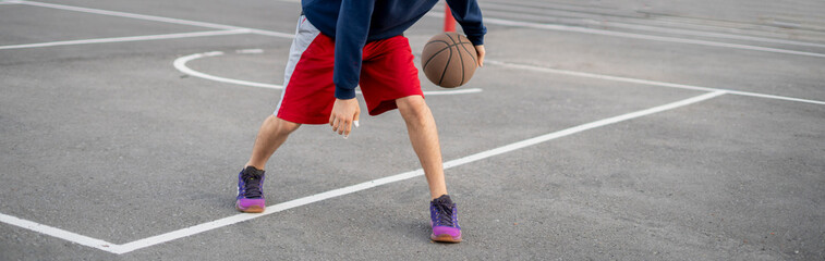 Naklejka premium young basketball player training to dribble outdoor on the asphalt court in summer seasons
