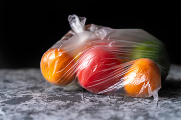 damaged spoiled fruits in a bag in a dark room, plastic container harm concept b