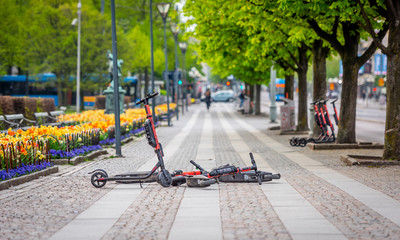 Electric scooters lying on the pavement creating danger for pedestrians.