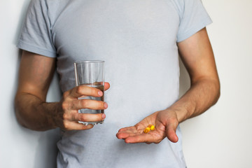  young  man holding a glass of water  and pills