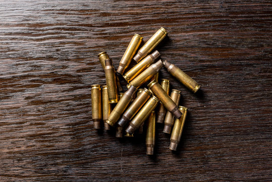 Empty bullet casings on a dark, wooden table.