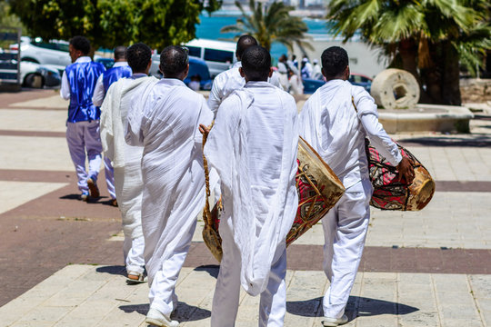 Group ethiopian mens dressed in traditional white clothes carrying kebero drums
