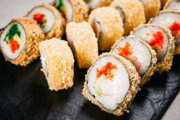 Tempura maki sushi rolls set on black slate. Japanese traditional fusion food style, restaurant menu background, degustation, buffet