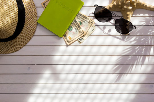 Traveler Accessories, Passport With Cash Money US Dollars, Tropical Palm Leaf Branches On White Background With Empty Space For Text. Travel Vacation Concept. Summer Background. Flat Lay, Top View.