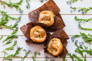 Fresh baked pastry with blue spring flowers on wooden table. Food, dessert concept. Sugar dessert with cream 