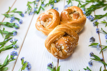 Fresh baked pastry with blue spring flowers on wooden table. Food, dessert concept. Sugar dessert with cream 