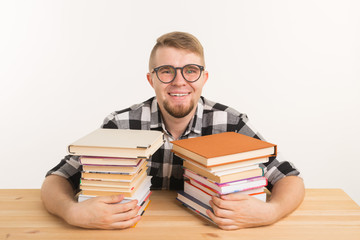People, knowledge and education concept - smiling man sitting at the wooden table with books