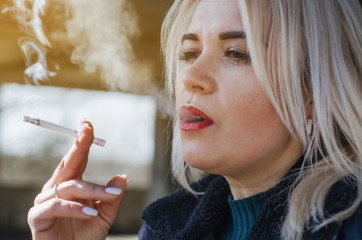 Obraz premium Woman with white hair smokes a cigarette, closeup portrait