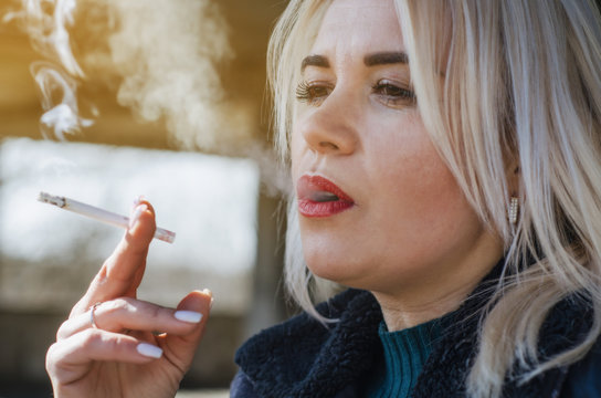 Woman with white hair smokes a cigarette, closeup portrait