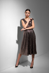 Fototapeta premium Young fashion woman in cocktail dress with sequins. Dark hair, posing in studio