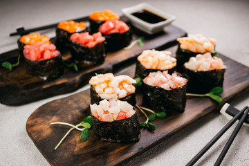 Seafood delicatessen gunkan maki sushi rolls on wooden plates. Different gourmet snacks. Luxury lifestyle, expensive food, restaurant menu