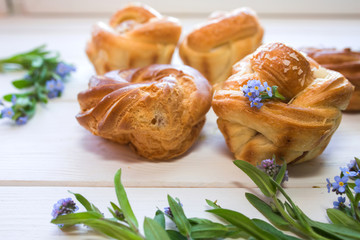 Fresh baked pastry with blue spring flowers on wooden table. Food, dessert concept. Sugar dessert with cream 