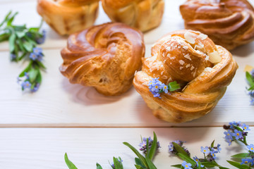 Fresh baked pastry with blue spring flowers on wooden table. Food, dessert concept. Sugar dessert with cream 