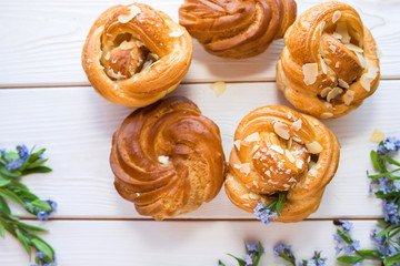 Fresh baked pastry with blue spring flowers on wooden table. Food, dessert concept. Sugar dessert with cream 