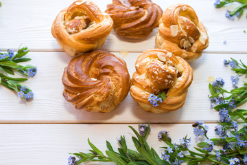 Fresh baked pastry with blue spring flowers on wooden table. Food, dessert concept. Sugar dessert with cream 