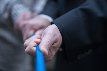Pull together on a blue rope, human hands of male persons, business