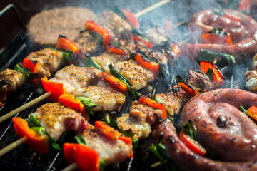 Obraz na płótnie Canvas Close up pf delicious chicken breast on wooden skew with fresh vegetables, garlic, paprika fried on mangal barbeque grill and smoke