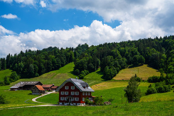 Fototapeta na wymiar Colorful view of idyllic mountain scenery in the Alps with fresh green meadows on a beautiful day in summer. The UNESCO Biosphere reserve Entlebuch is the perfect slow-down hotspot near Lucerne.