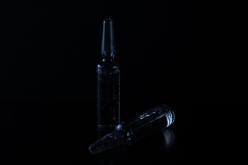 ampoules and syringe on black background