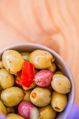 Olives stuffed, red pepper and spices of herbs. Multi-colored olives in a gray bowl on a rustic table. Blurry background. Macro. Soft focus. Copy space. Top view.