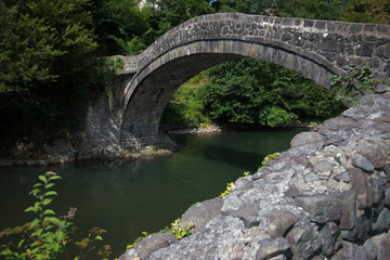 Fototapeta na wymiar Old historic stone bridge over river.