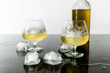 Glass of cognac with ice and ice spilled on the table
