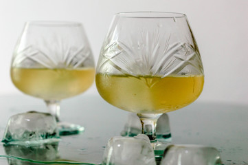 Glass of cognac with ice and ice spilled on the table