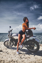 sexy asian woman near her vintage custom motorcycle