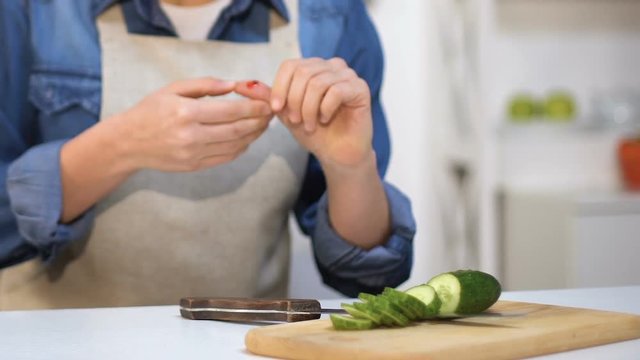 Inexperienced girl cutting her finger making vegetable salad, household injury