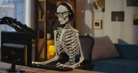 Skeleton with headphone sitting at computer