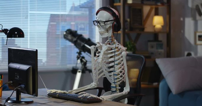 Skeleton with headphone sitting at computer