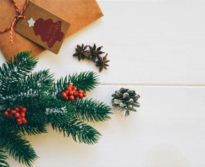 Christmas fir branches with decorations and gift on wooden white board. Toned image with copy space.