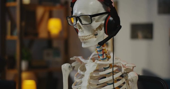 Skeleton with headphone sitting at computer