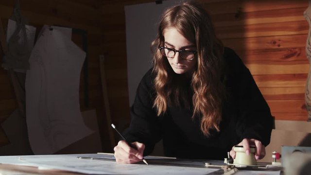 Inspired female architect drawing an architectural plan on the big table indoors.