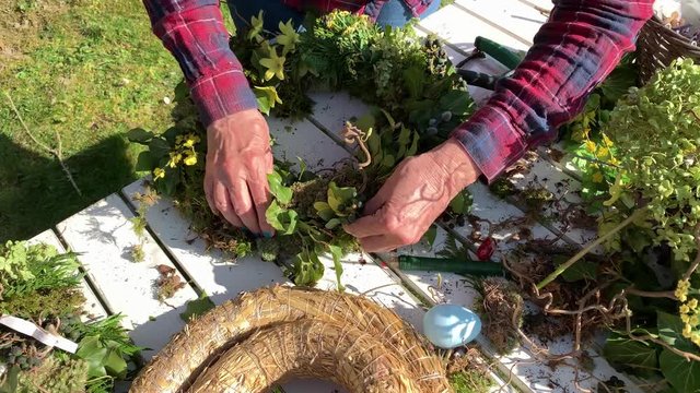 Mother and daughter tie easter wreaths, spring wreaths, summer wreaths outdoors in sunshine and are happy