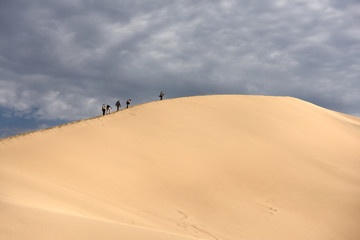 Fototapeta na wymiar Group of photographers climbing Singing Sand Dune Altyn Emel National Park Kazakhstan