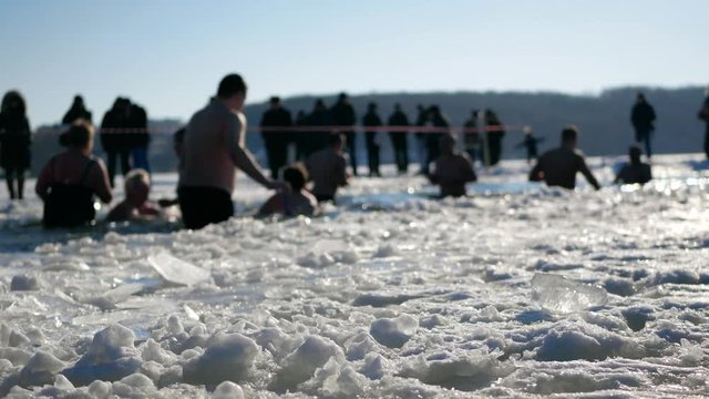 Bathing in cold ice water. Mass festive celebratory hardening, winter swimming in freeze. Shocked people bathe in ice hole. Christmas New Year holidays. Epiphany. Baptism of the Lord