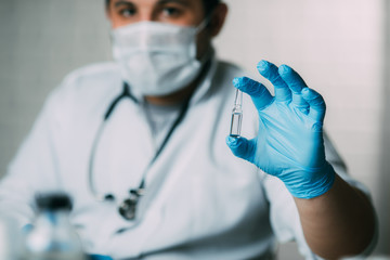 Doctor in blue gloves is holding a vial of demonstrating