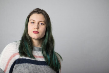Fototapeta premium Beautiful brunette girl with dyed green hair on white background.