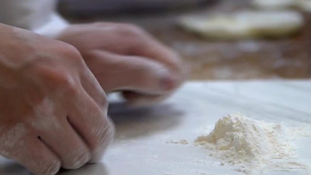A taiwanese team of chefs rolls out dough before filling it with meat to create jiaozi, a Chinese dumpling. Asian chef making fresh dumplings in the restaurant of Taipei. -Dan