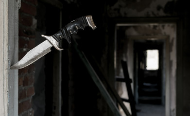 terrible fighting old knife stuck in the doorway on the background of the ruined corridor of the old abandoned house