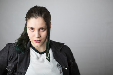 Fototapeta premium Beautiful brunette girl with dyed green hair on white background.