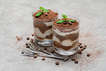 two portions Classic tiramisu dessert in a glass on concrete background