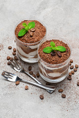 two portions Classic tiramisu dessert in a glass on concrete background